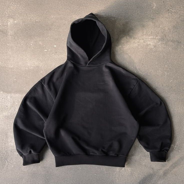 Black pullover hoodie laid flat on concrete