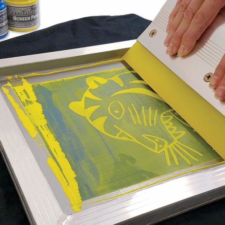 Yellow ink being applied through a screen onto a garment