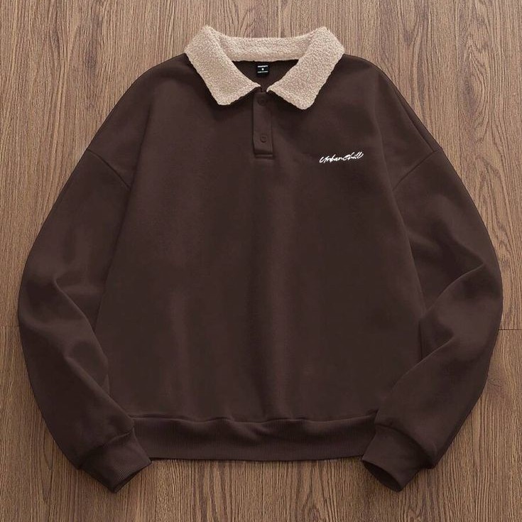 Brown sweatshirt with a cream fleece collar laid flat on wood