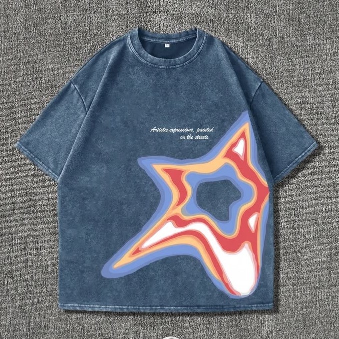 Washed blue T-shirt with a multicoloured star graphic laid flat on grey fabric